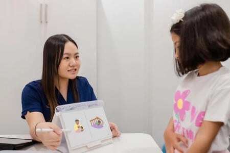 A Speech Pathologist from SASHC conducting a speech therapy session with a young child, using visual prompts to improve communication, comprehension, and articulation skills.